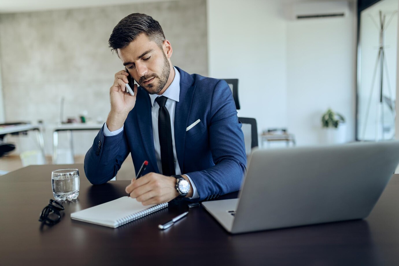 joven empresario escribiendo notas mientras habla telefono oficina 637285 8726